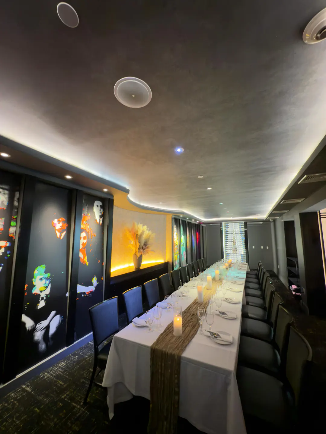 The private dining room: one long table set with candles under a curved, softly lit ceiling, portraits along the wall.